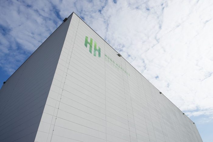 Gewerbebau mit weißen Wandplatten und grünem Hugo Häffner Logo